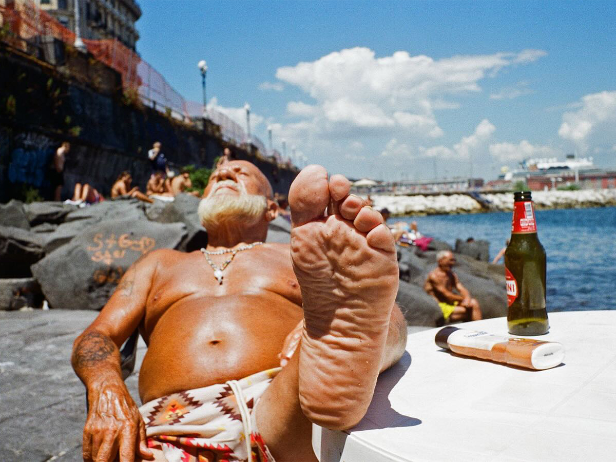 Man reclining on beach in Naples by photographer Robbie McIntosh