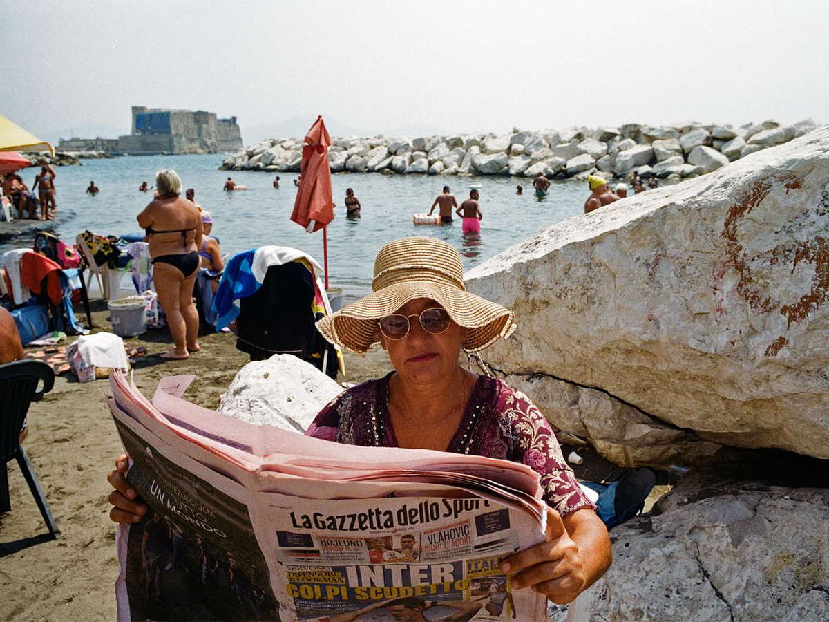 Woman reading newspaper at the beach in Naples, Italy