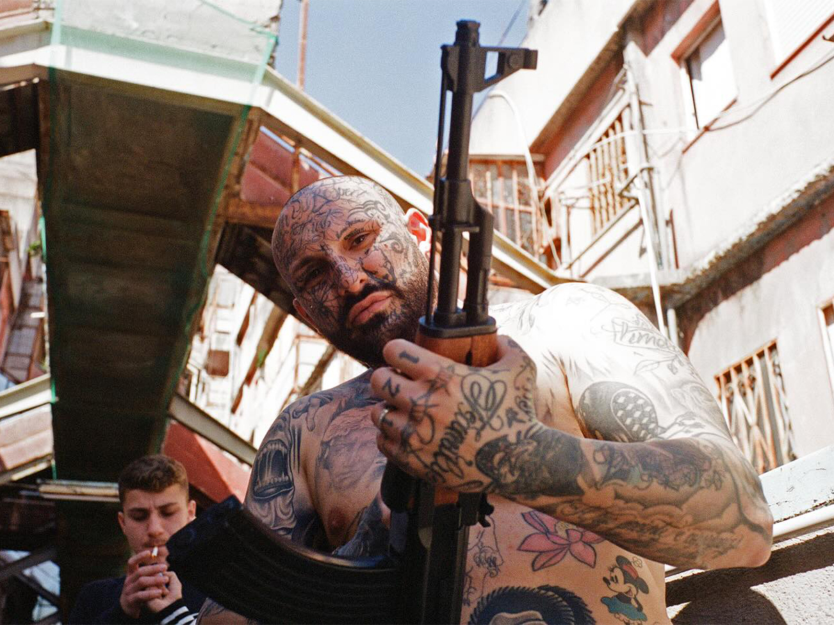 Tattooed man with machine gun in Naples, Italy